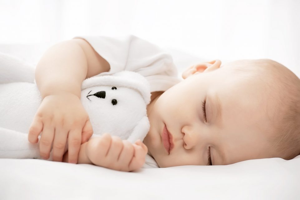 Carefree sleep little baby with a soft toy on the bed